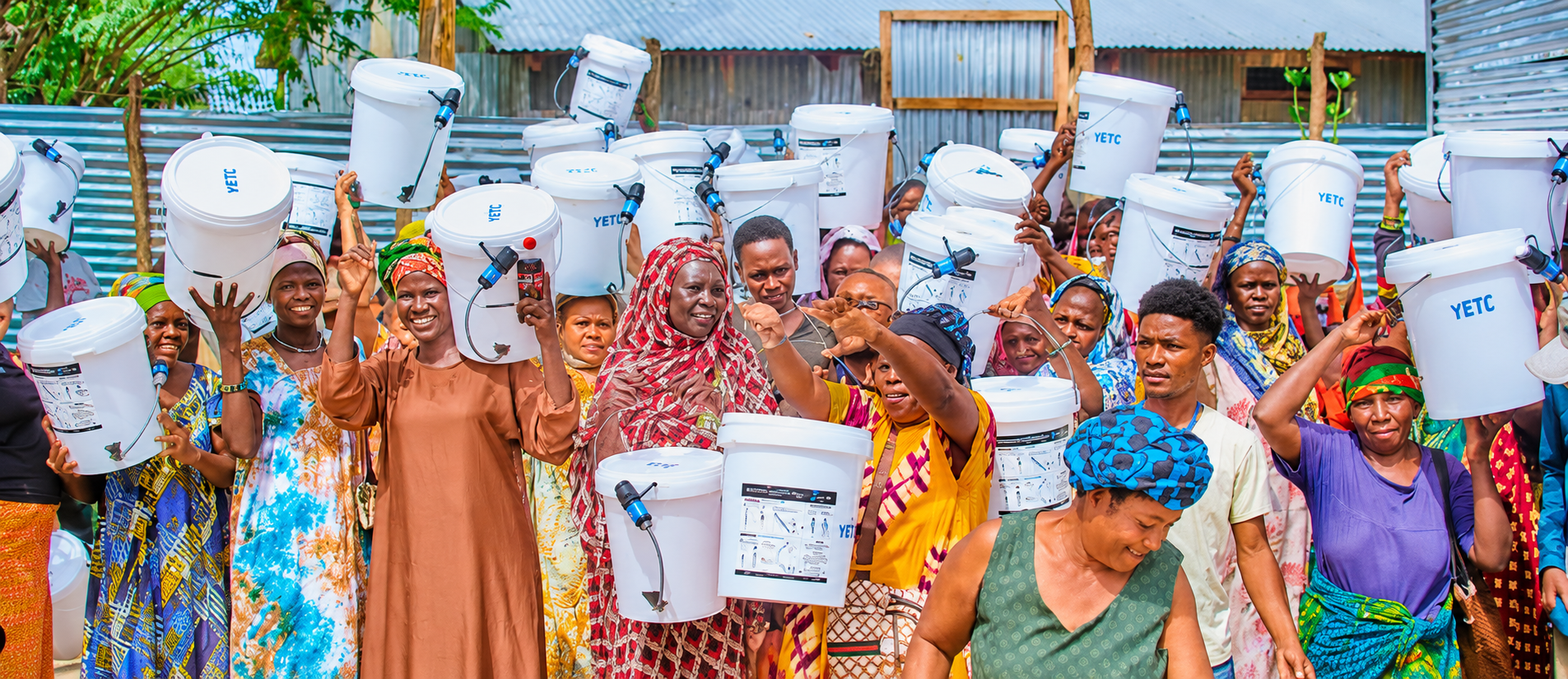 Community members in Kakuma holding white YETC water filtration buckets